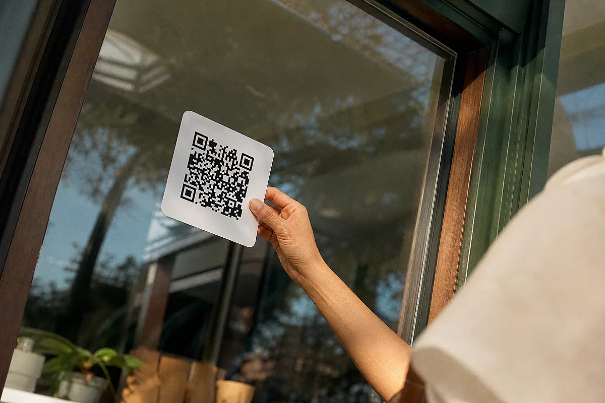 Dükkân sahibi QR etiketini vitrin camına yapıştırıyor